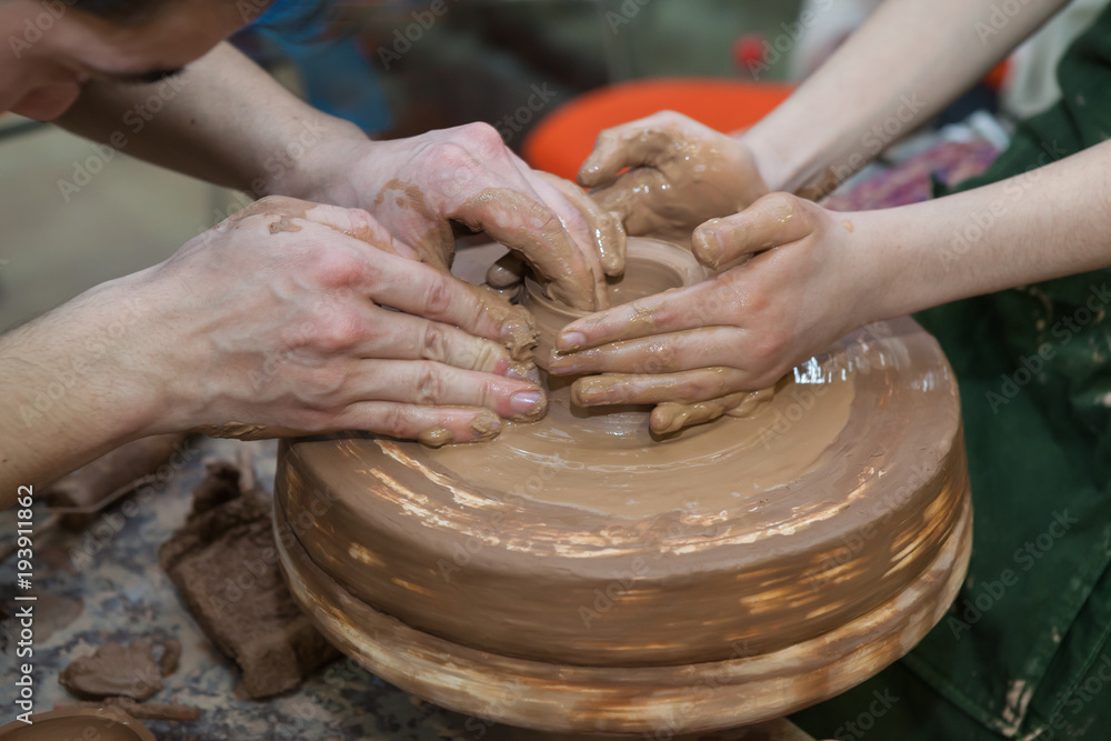 The teacher conducts a master class on sculpting from clay on a Potter's wheel in the pottery workshop.Top view closeup.