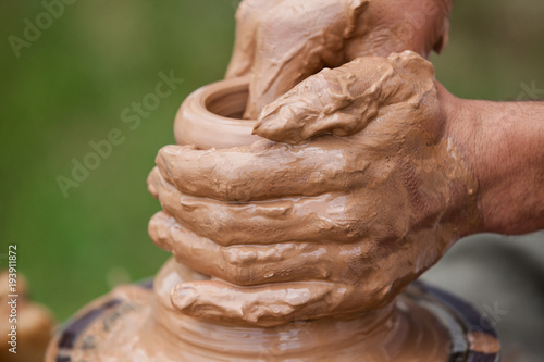 Create vases from clay close up. Hands of a master make a clay pitcher on a Potter's wheel.