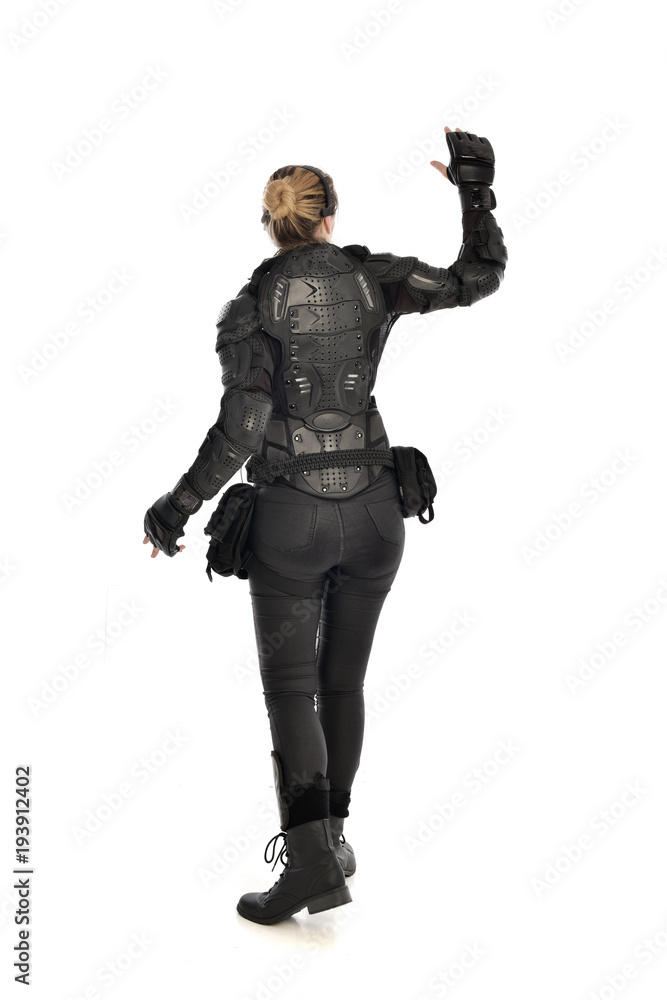 full length portrait of female soldier wearing black tactical armour facing away from camera, isolated on white studio background. full length portrait of female soldier wearing black tactical armour facing away from camera, isolated on white studio background.