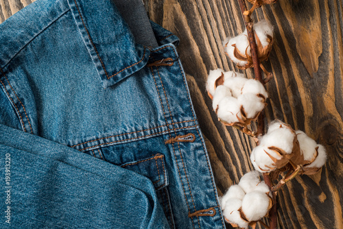 Details denim jacket, dried cotton flowersback jacket jeans texture-wooden background photo