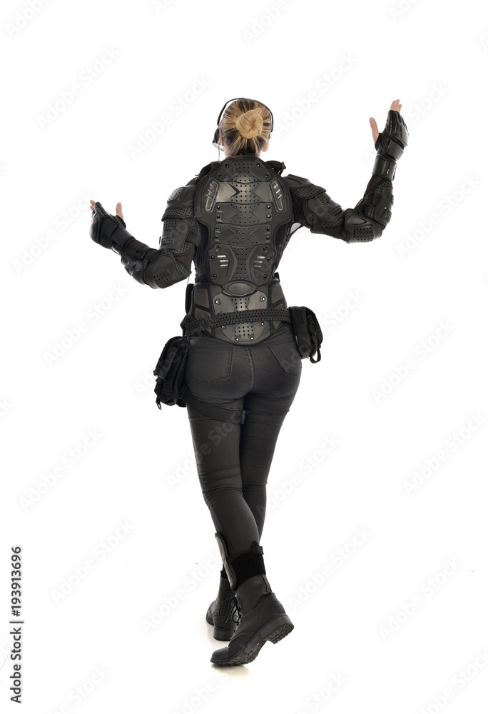 full length portrait of female soldier wearing black tactical armour facing away from camera, isolated on white studio background. full length portrait of female soldier wearing black tactical armour facing away from camera, isolated on white studio background.