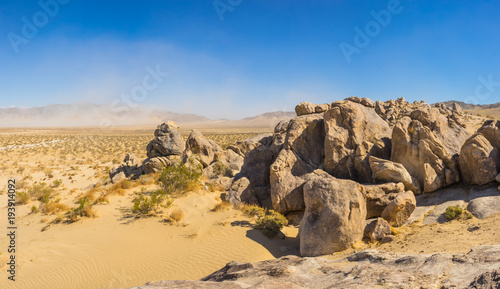 Panorama of boulders above a vast plain of sand and desert in southern California.