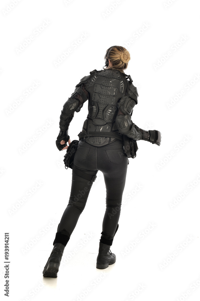full length portrait of female soldier wearing black tactical armour facing away from camera, isolated on white studio background. full length portrait of female soldier wearing black tactical armour facing away from camera, isolated on white studio background.