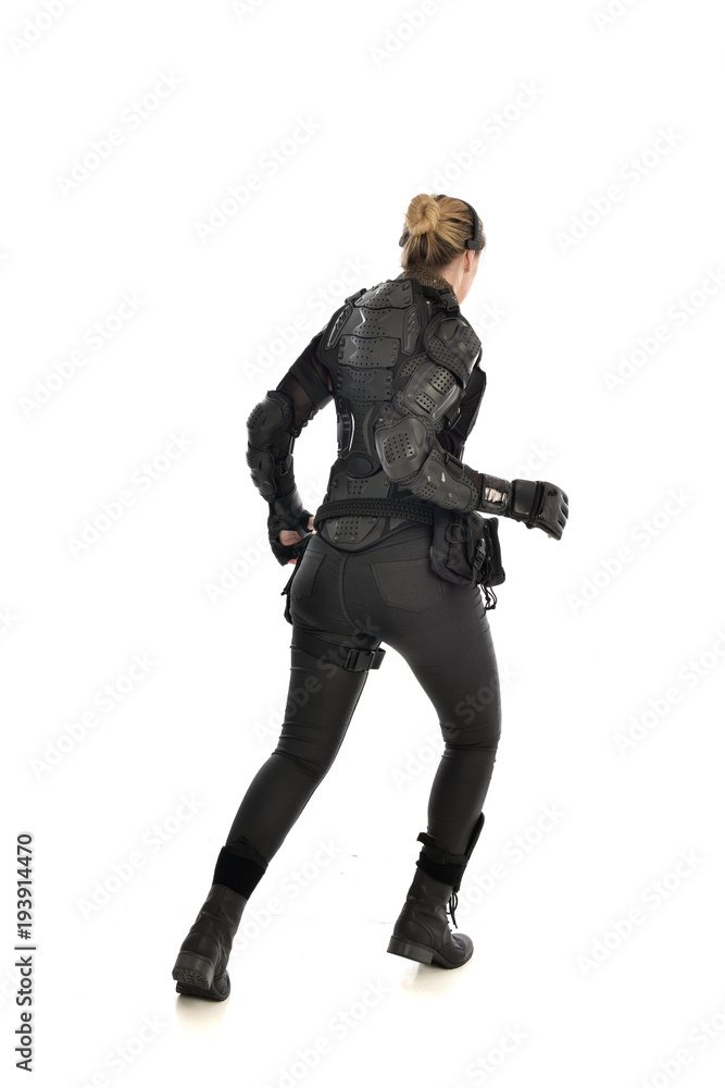 full length portrait of female soldier wearing black tactical armour facing away from camera, isolated on white studio background. full length portrait of female soldier wearing black tactical armour facing away from camera, isolated on white studio background.
