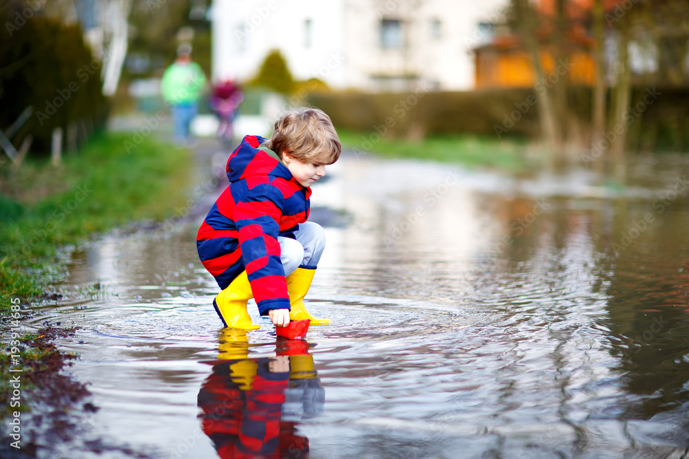 Happy little kid boy in yellow rain 