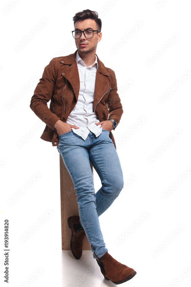 fashion man sitting on wooden box with hands in pockets fashion man sitting on wooden box with hands in pockets