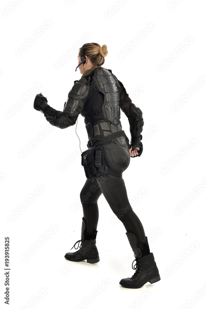full length portrait of female soldier wearing black tactical armour facing away from camera, isolated on white studio background. full length portrait of female soldier wearing black tactical armour facing away from camera, isolated on white studio background.