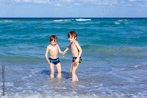 Two kid boys running on ocean beach. Little children having fun © Irina Schmidt