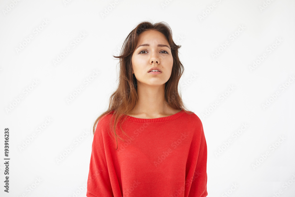 Horizontal studio shot of attractive young mixed race lady with brown loose hair looking at camera with lips slightly parted, having suspicious expression of her cute face. Human emotions and reaction Horizontal studio shot of attractive young mixed race lady with brown loose hair looking at camera with lips slightly parted, having suspicious expression of her cute face. Human emotions and reaction