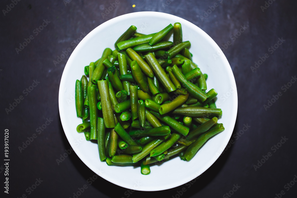 Cooked green beans in white plate on black background, Close up, top view. healthy food, proper nutrition. Cooked green beans in white plate on black background, Close up, top view. healthy food, proper nutrition.