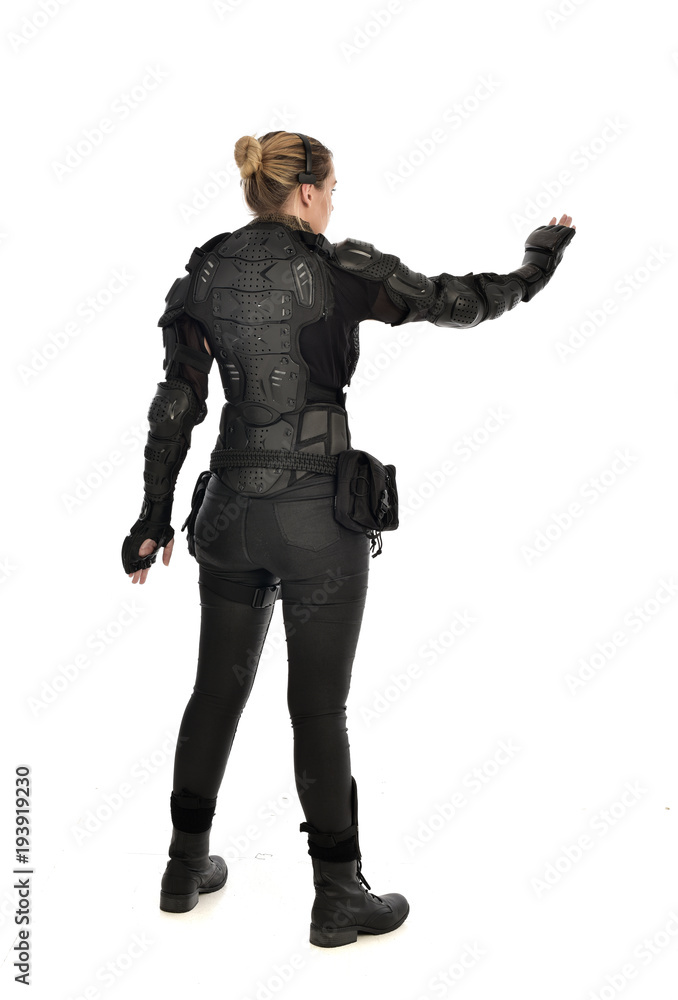 full length portrait of female soldier wearing black tactical armour facing away from camera, isolated on white studio background. full length portrait of female soldier wearing black tactical armour facing away from camera, isolated on white studio background.