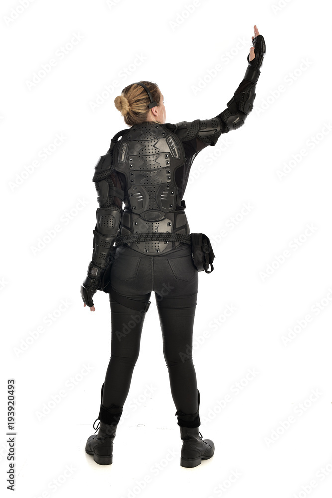 full length portrait of female  soldier wearing black  tactical armour  facing away from camera, isolated on white studio background.