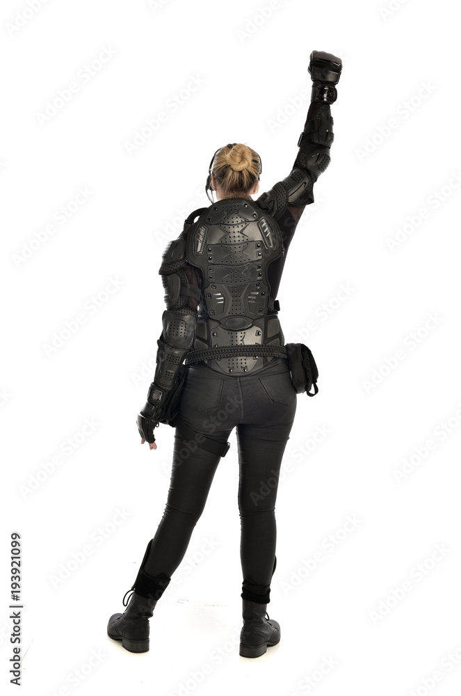 full length portrait of female soldier wearing black tactical armour facing away from camera, isolated on white studio background. full length portrait of female soldier wearing black tactical armour facing away from camera, isolated on white studio background.