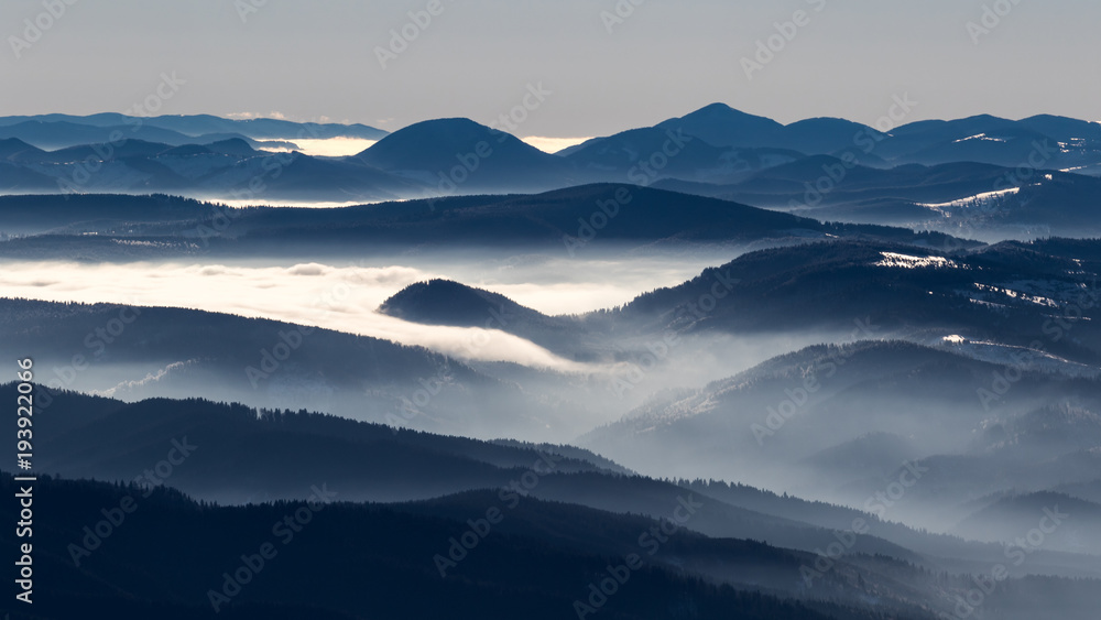 A frozen morning on top of Ciucas mountains in Romania with some beautiful clouds dancing in the valley bellow