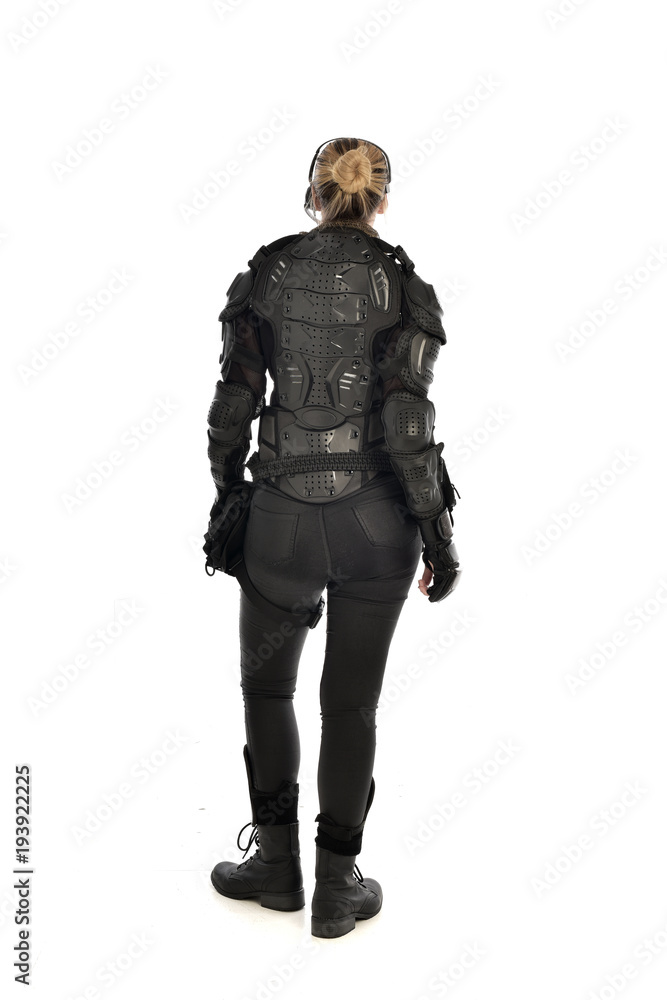 full length portrait of female  soldier wearing black  tactical armour  facing away from camera, isolated on white studio background.