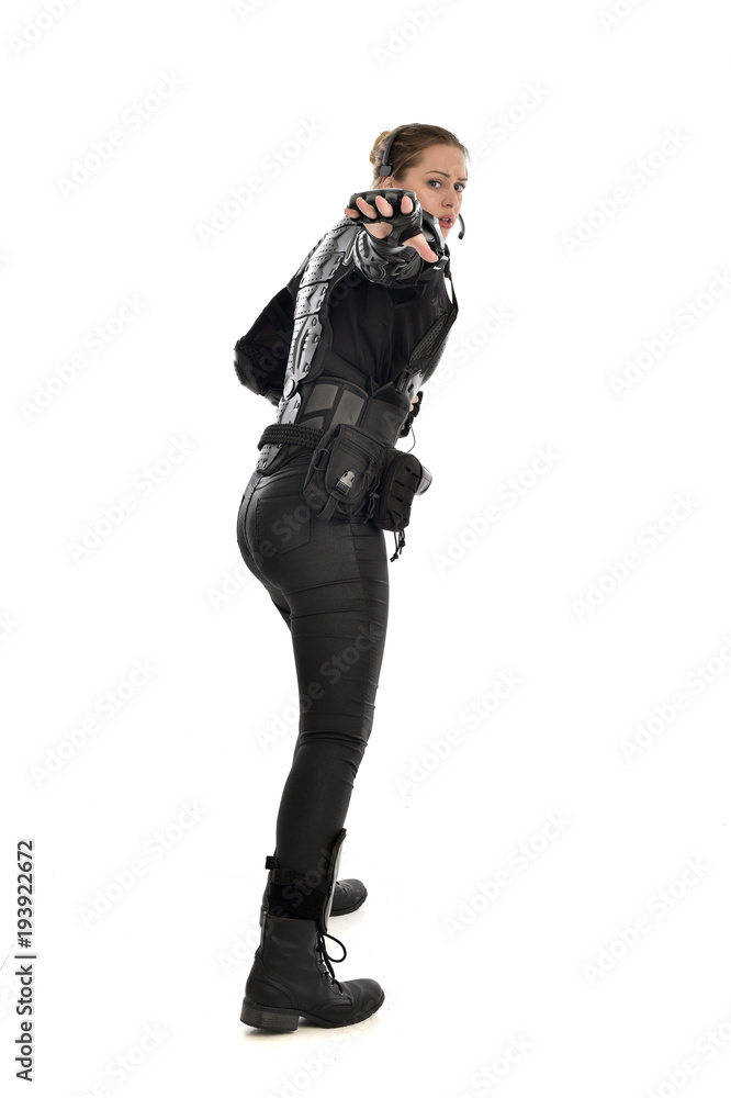 full length portrait of female soldier wearing black tactical armour facing away from camera, isolated on white studio background. full length portrait of female soldier wearing black tactical armour facing away from camera, isolated on white studio background.