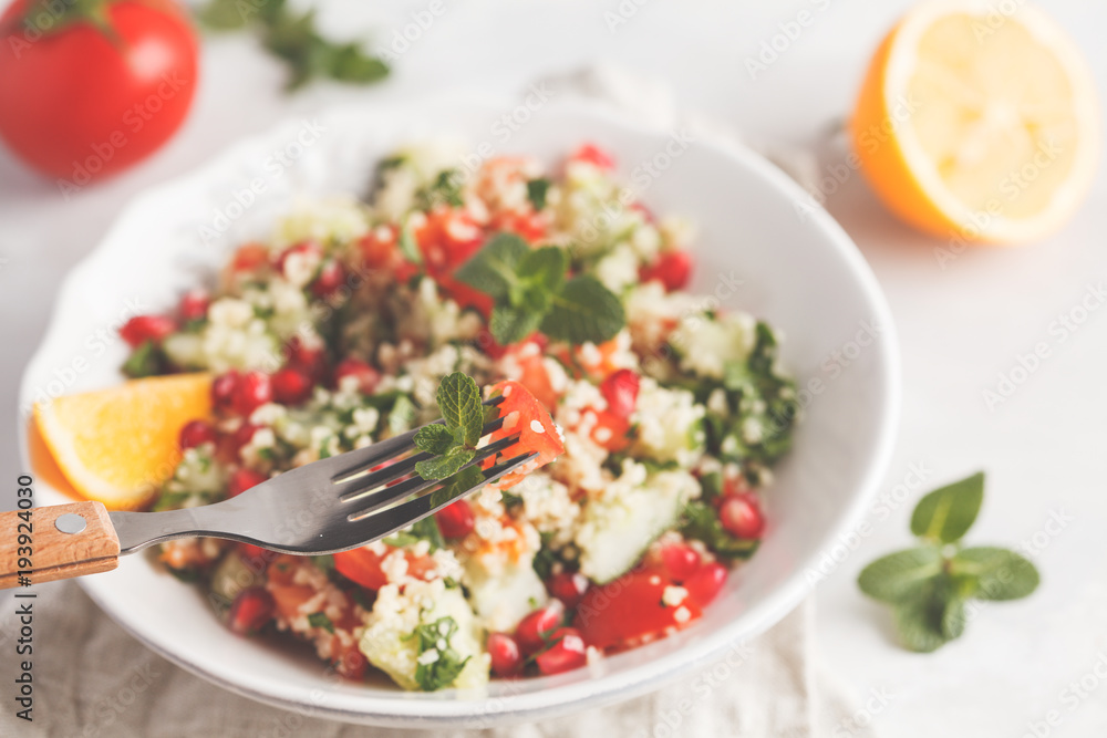 Tabbouleh salad with tomato, cucumber, couscous, mint and pomegranate. Vegan Healthy Food Concept. Traditional middle eastern or arab dish. Tabbouleh salad with tomato, cucumber, couscous, mint and pomegranate. Vegan Healthy Food Concept. Traditional middle eastern or arab dish.