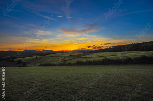 beautiful sunset landscape over the green hills 