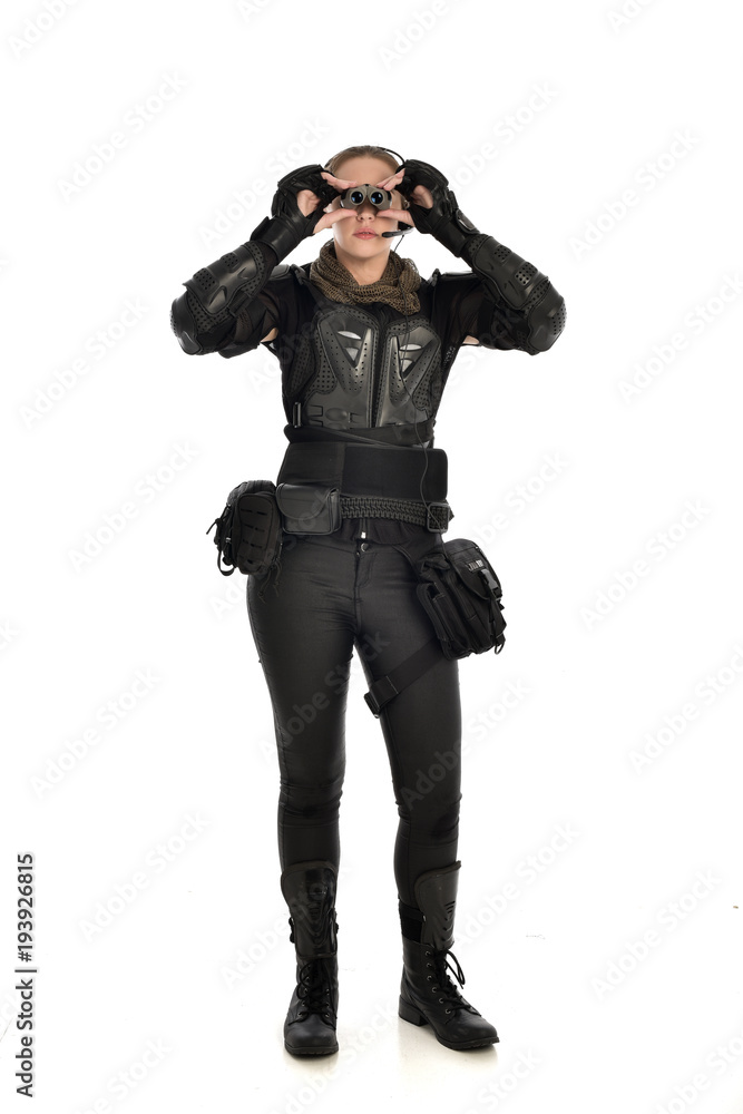 full length portrait of female soldier wearing black tactical armour holding a pair of binoculars, isolated on white studio background. full length portrait of female soldier wearing black tactical armour holding a pair of binoculars, isolated on white studio background.