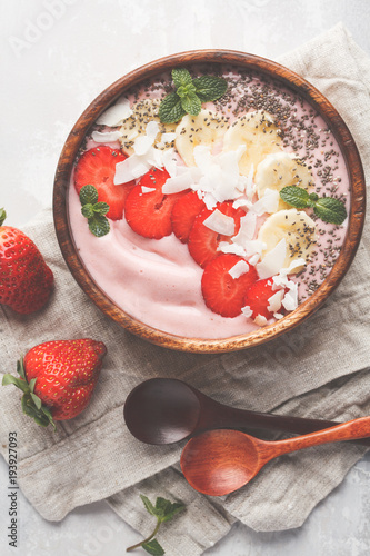 Strawberry pink smoothie bowl with banana, coconut and chia seeds, top view. Healthy vegan food concept.