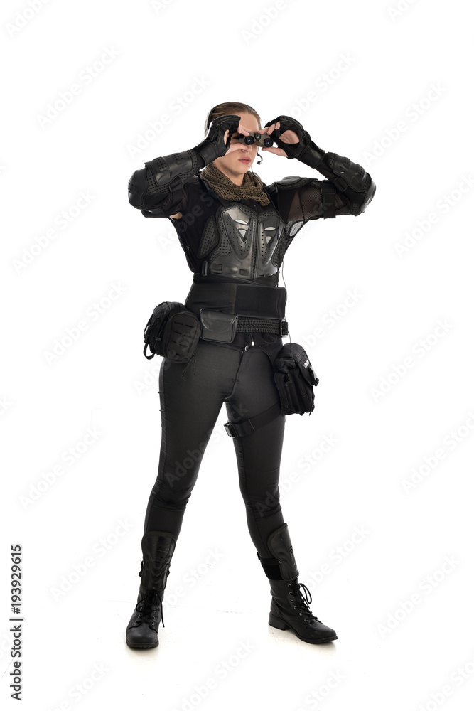 full length portrait of female soldier wearing black tactical armour holding a pair of binoculars, isolated on white studio background. full length portrait of female soldier wearing black tactical armour holding a pair of binoculars, isolated on white studio background.
