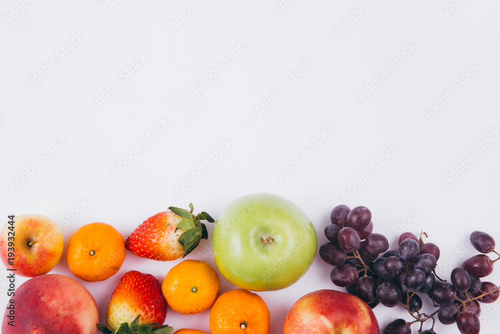 A variety of colorful fruits placed at the bottom in white background with copy space, healthy and organic food concept A variety of colorful fruits placed at the bottom in white background with copy space, healthy and organic food concept