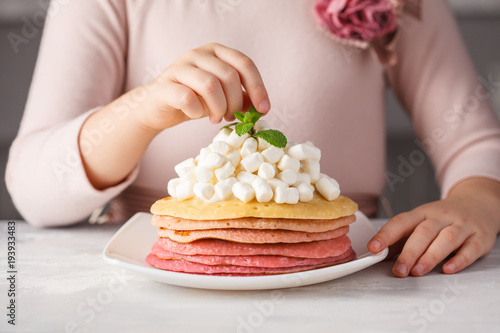 Child girl cooking and eating pink ombre pancakes with marshmallow. The child food concept.