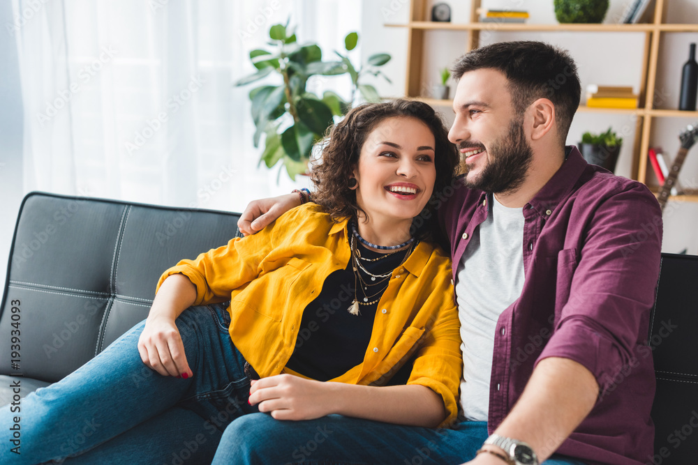 Fototapeta premium Happy smiling couple sitting on leather sofa
