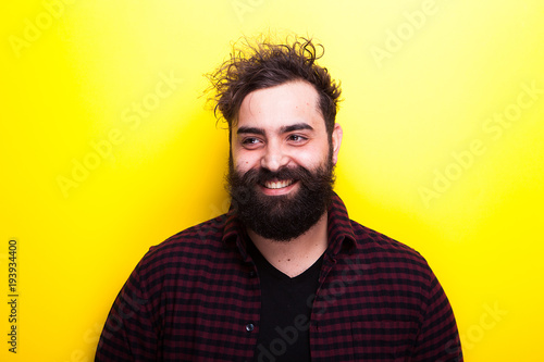 Caucasian bearded hipster smiling on yellow background