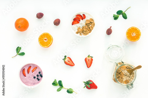 Fototapeta Naklejka Na Ścianę i Meble -  Healthy breakfast with yogurt, muesli, fruits, orange, berry, strawberry, blueberries on white background, flat lay, top view