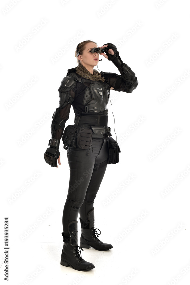 full length portrait of female soldier wearing black tactical armour holding a pair of binoculars, isolated on white studio background. full length portrait of female soldier wearing black tactical armour holding a pair of binoculars, isolated on white studio background.