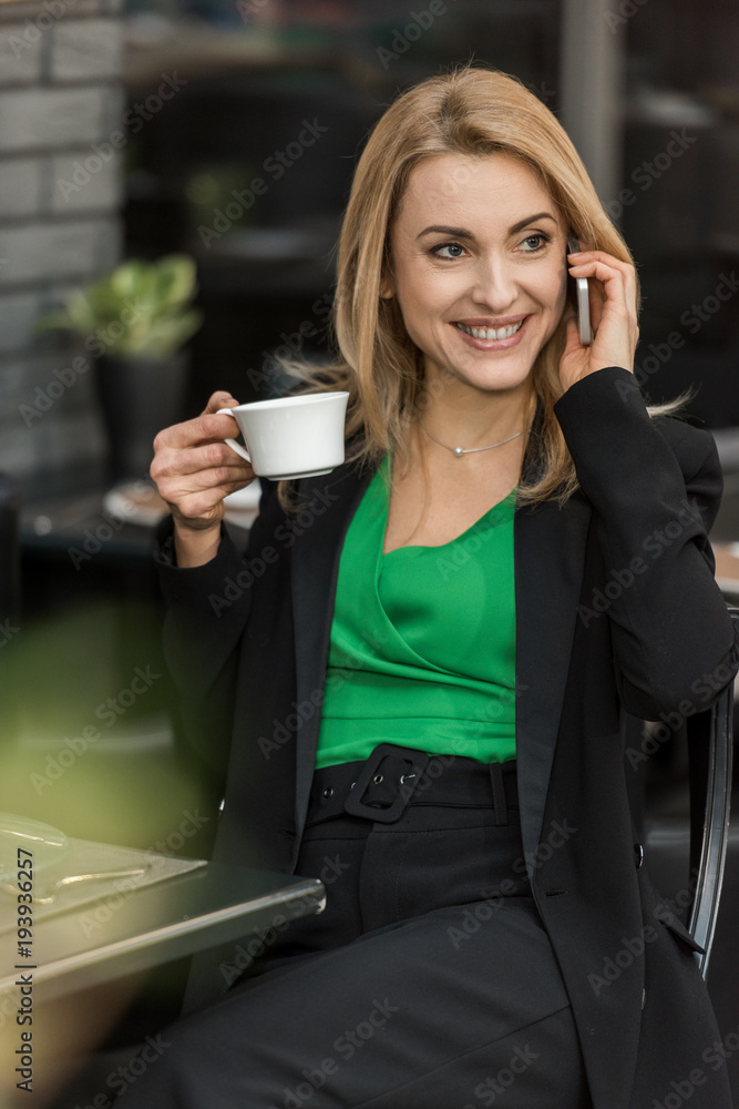 portrait of smiling woman with cup of coffee talking on smartphone in cafe portrait of smiling woman with cup of coffee talking on smartphone in cafe