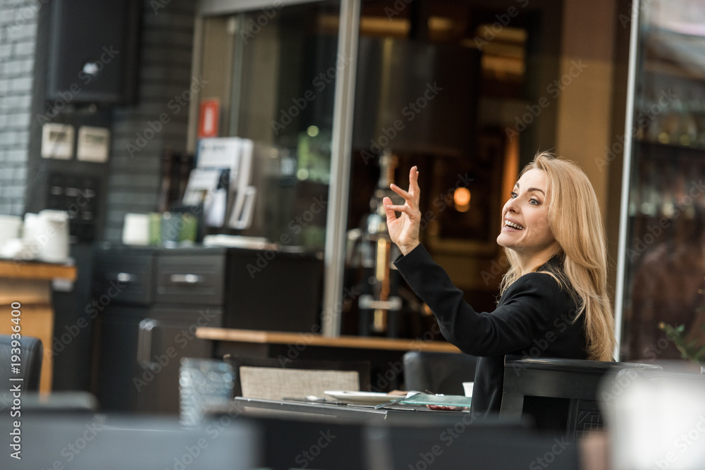 side view of smiling woman calling for waiter in restaurant side view of smiling woman calling for waiter in restaurant