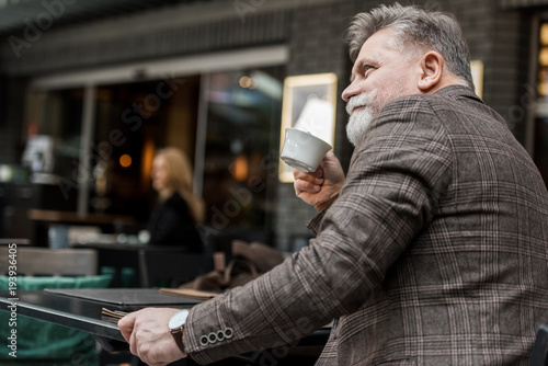side view of senior man with cup of coffee in cafe