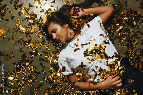 woman on the floor with golden confetti photo