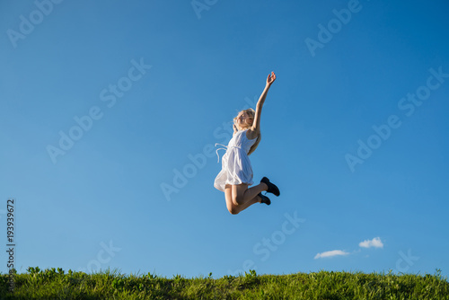 full lenth portrait of young woman is jumping on the meadow