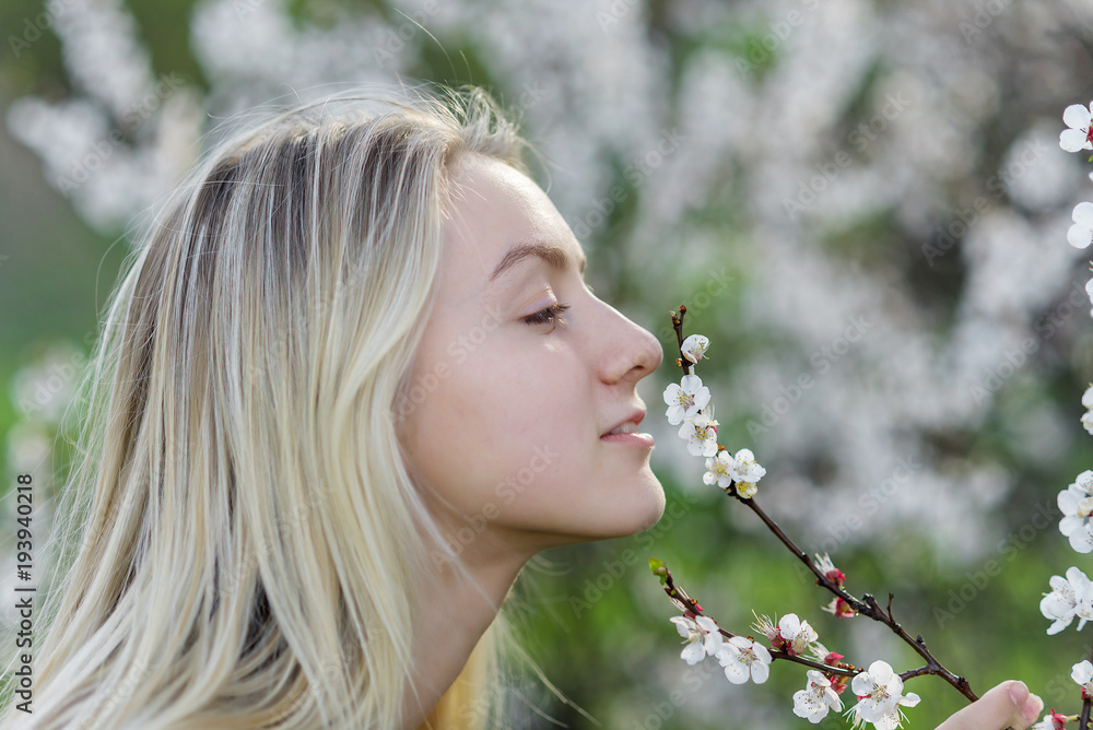 Closeup portrait of teenage girl inhales aroma of flowering apricot trees in the garden Closeup portrait of teenage girl inhales aroma of flowering apricot trees in the garden
