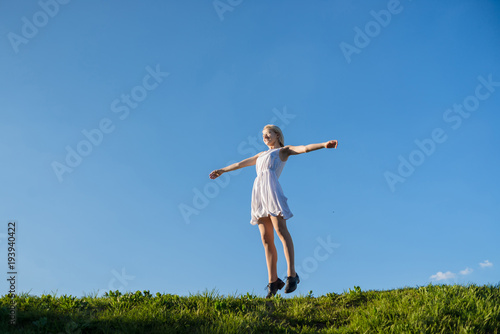 full lenth portrait of young woman is jumping on the meadow