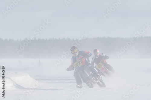 Motorcyclist racing on ice track in the middle of whirling snow