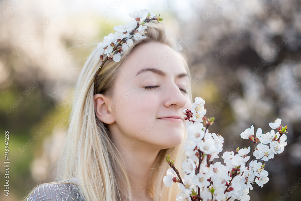 Closeup portrait of teenage girl inhales aroma of flowering apricot trees in the garden