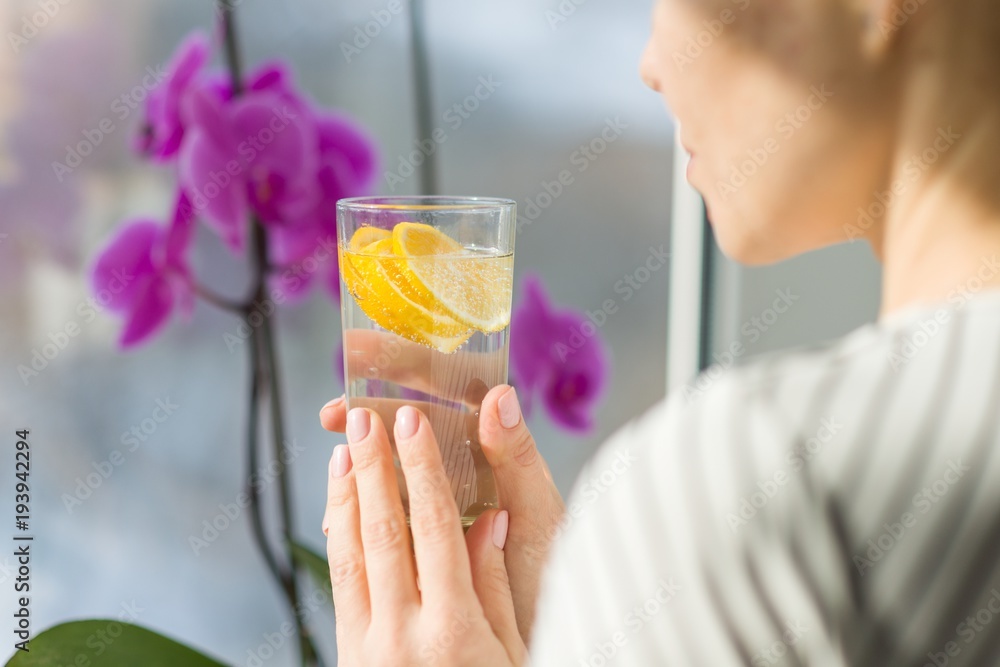 Fototapeta premium Woman drinking water with fresh organic lemon.