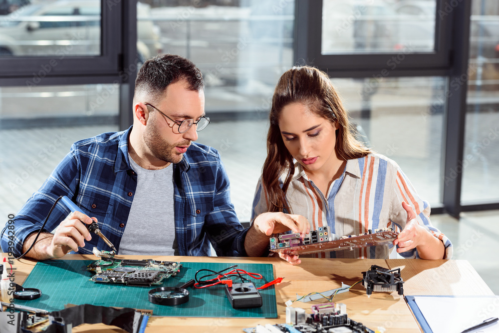 Fototapeta premium Man assisting woman in circuit board repair