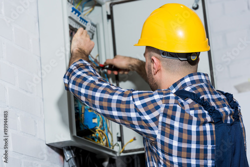 Male electrician checking wires in electrical box