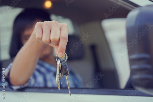 close up on driver man hand holding group of key over car's window for showing good rental service , business transportation concept