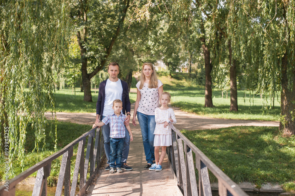 Mom and dad playing with their handsome son and daughter - Family and children outdoors in the park - Young beautiful family posing for the photographer Mom and dad playing with their handsome son and daughter - Family and children outdoors in the park - Young beautiful family posing for the photographer