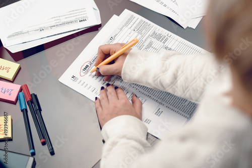 Woman fills the tax form, working with tax documents.Form 1040 Individual Income Tax return form. United States Tax forms 2017/2018.