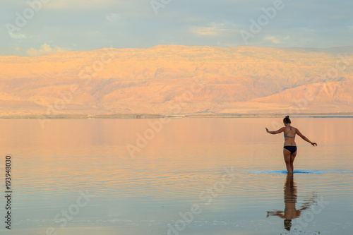 Young woman bathe in Dead Sea, Israel..Landscape Dead Sea Coast, rest and treatment at the Dead Sea resorts.