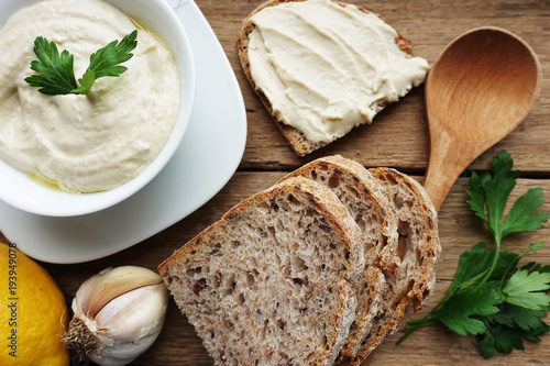 Tasty chickpeas hummus with olive oil, garlic and parsley, served on fresh wholegrain bread 