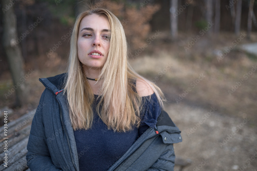 Obraz premium Beautiful natural young blonde woman wearing winter coat outside in the park winter time