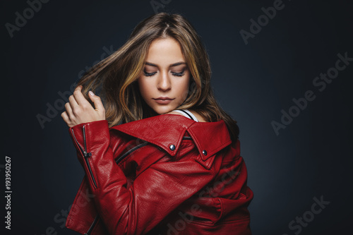Portrait of a young woman in a red leather jacket in studio